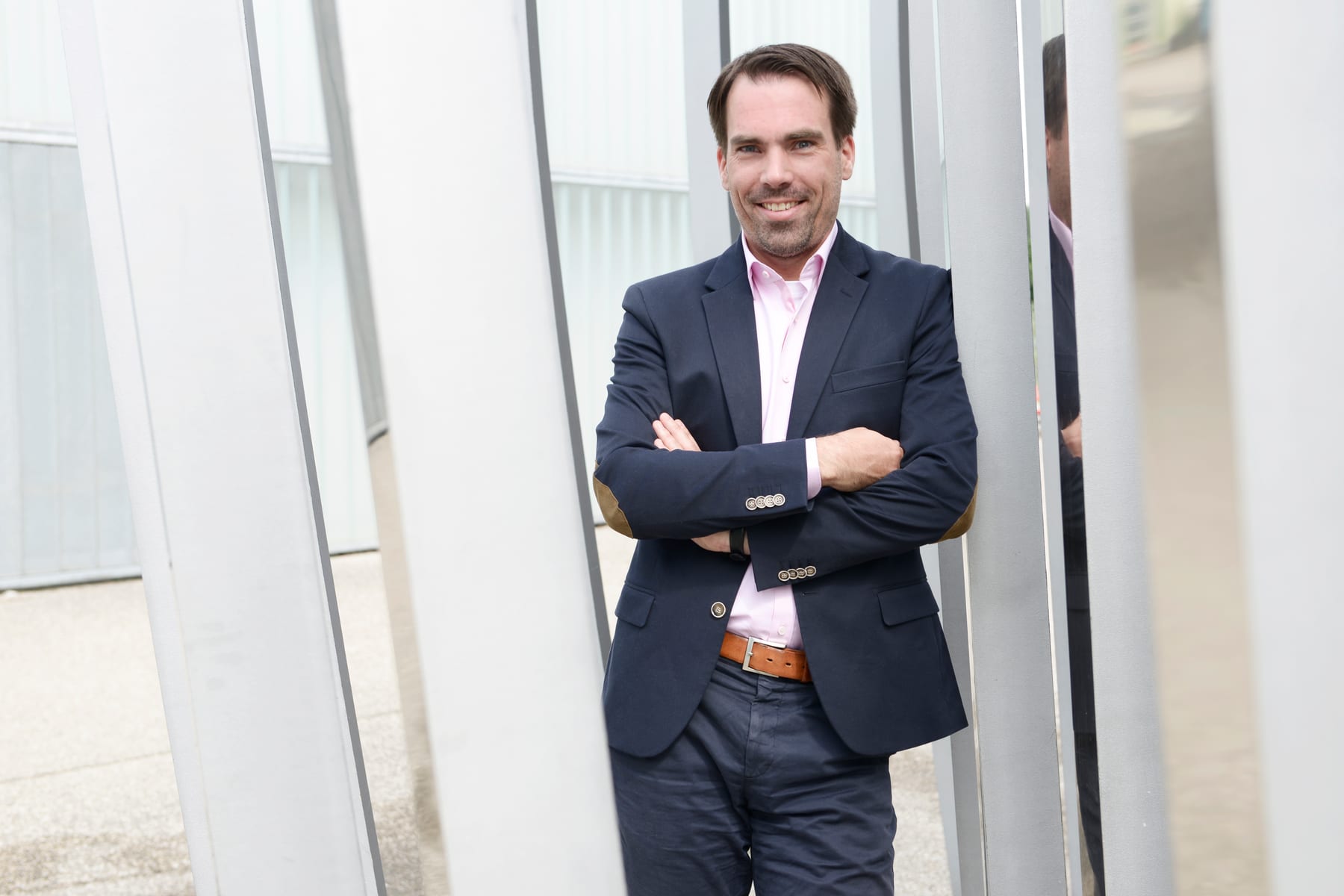Mann im Anzug lehnt an einer hellen Fassade