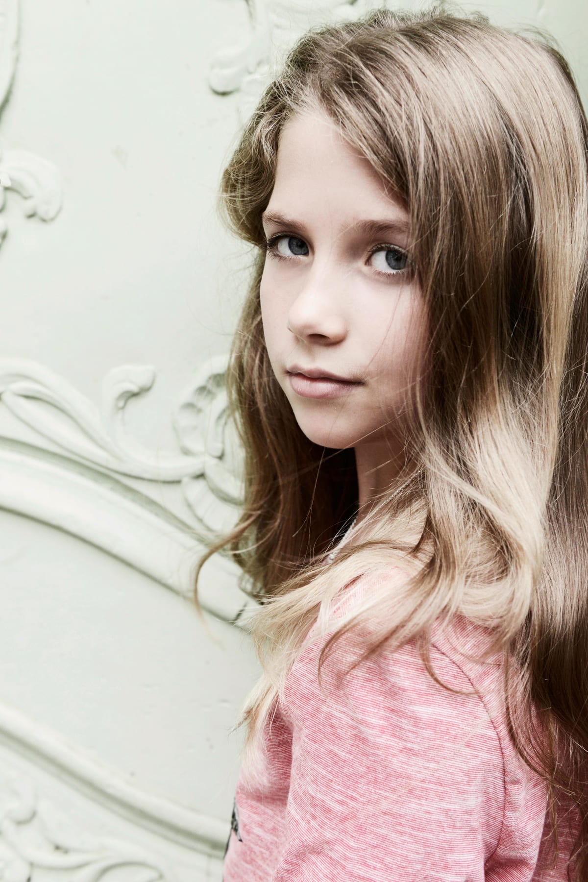 Mädchen mit langem Haar vor einer hellen Wand