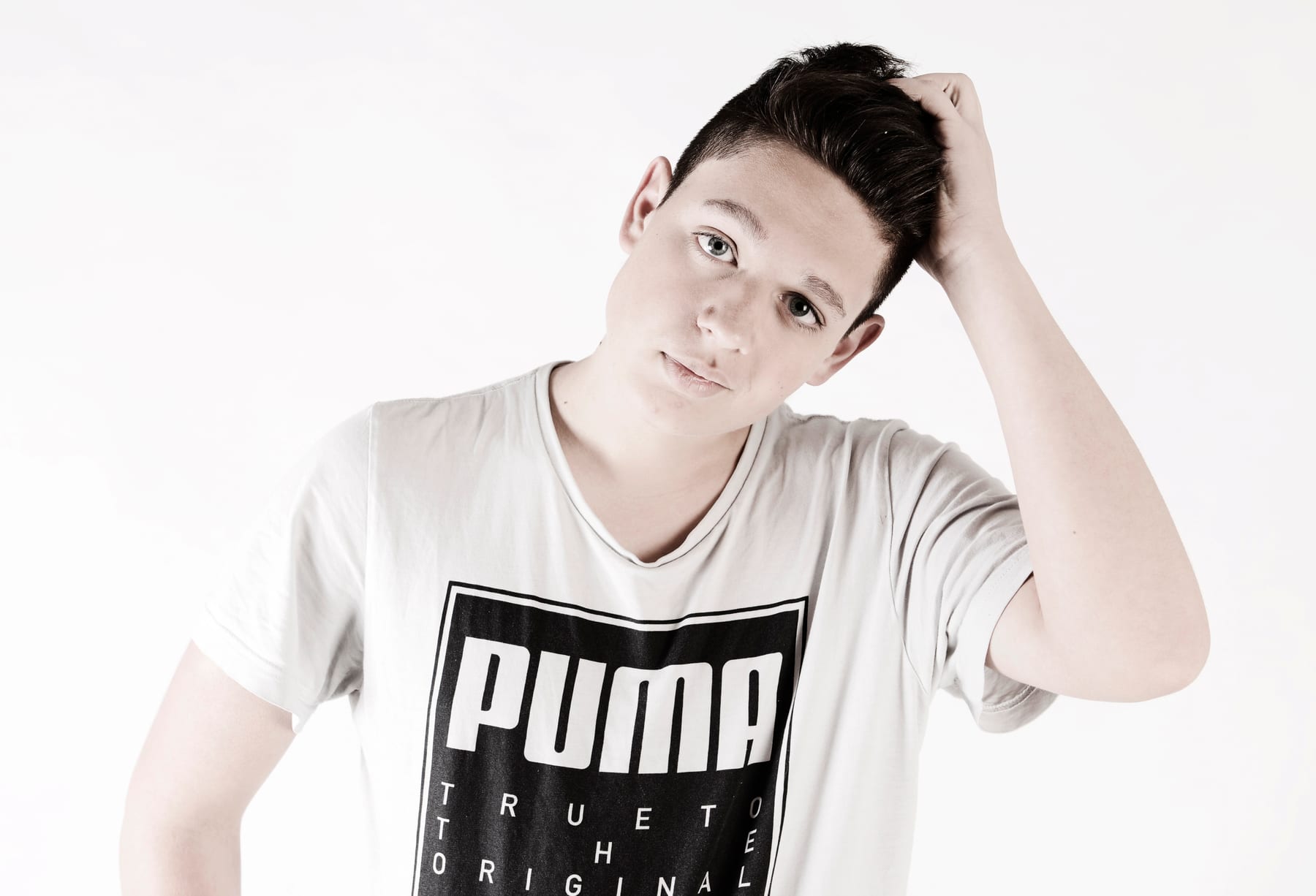 Junger Mann im weißen Shirt fährt sich durchs Haar