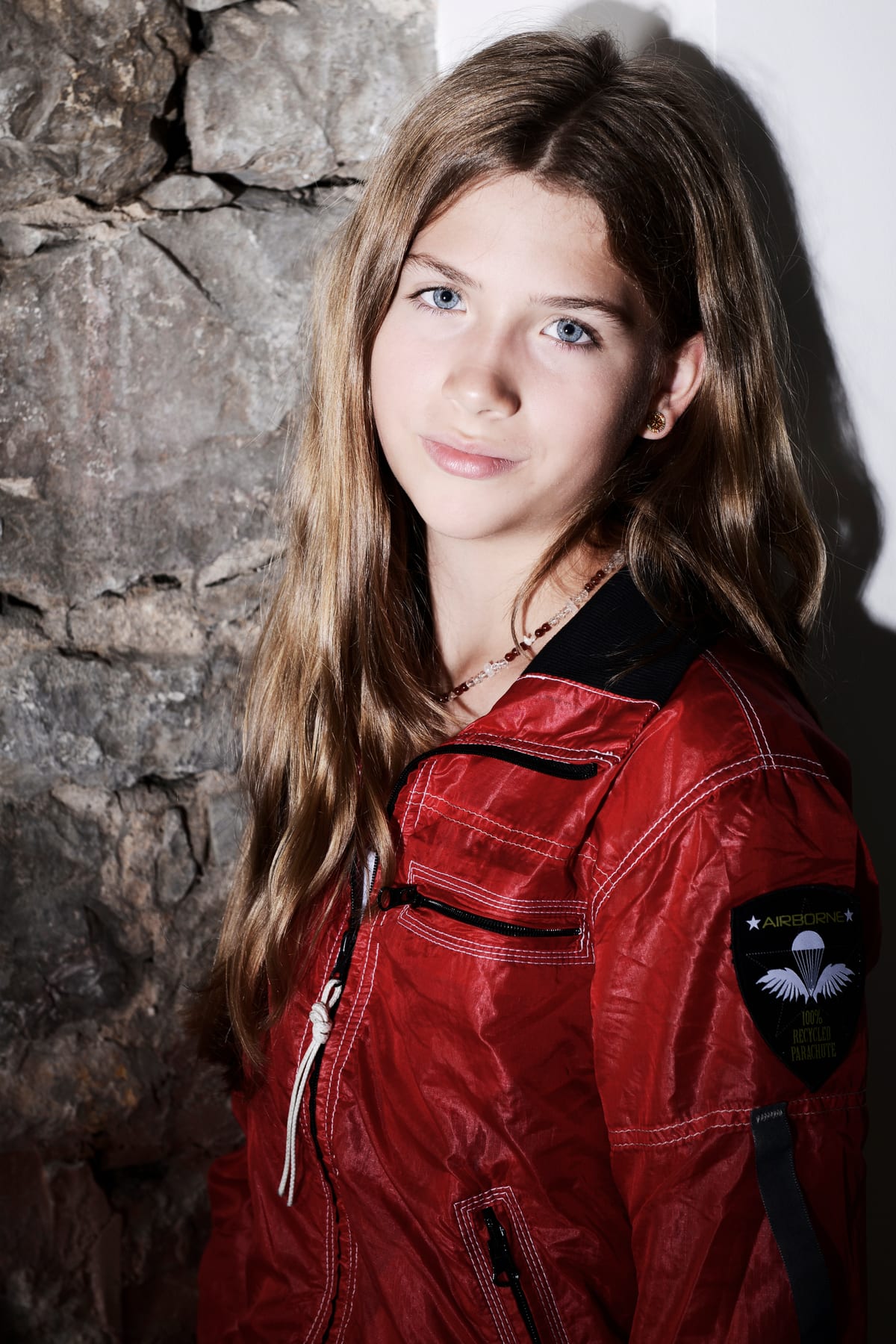 Junge Frau in roter Lederjacke vor einer Steinwand